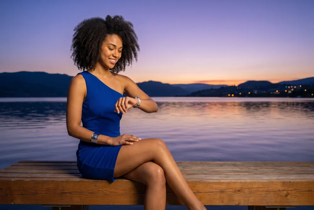 Character created for this guide: a young woman in a royal-blue dress on a lakeside bench at dusk, checking her wristwatch